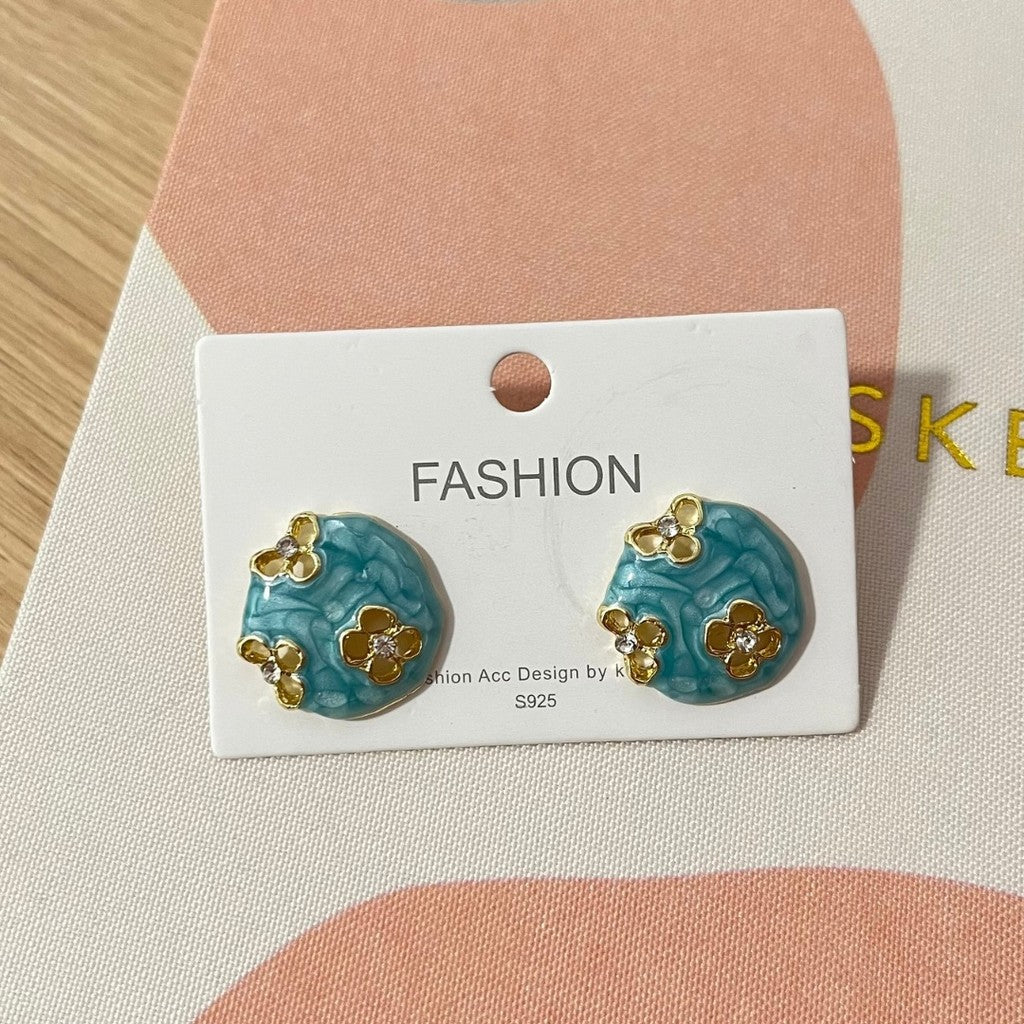 Aretes stud celestes con flores doradas.