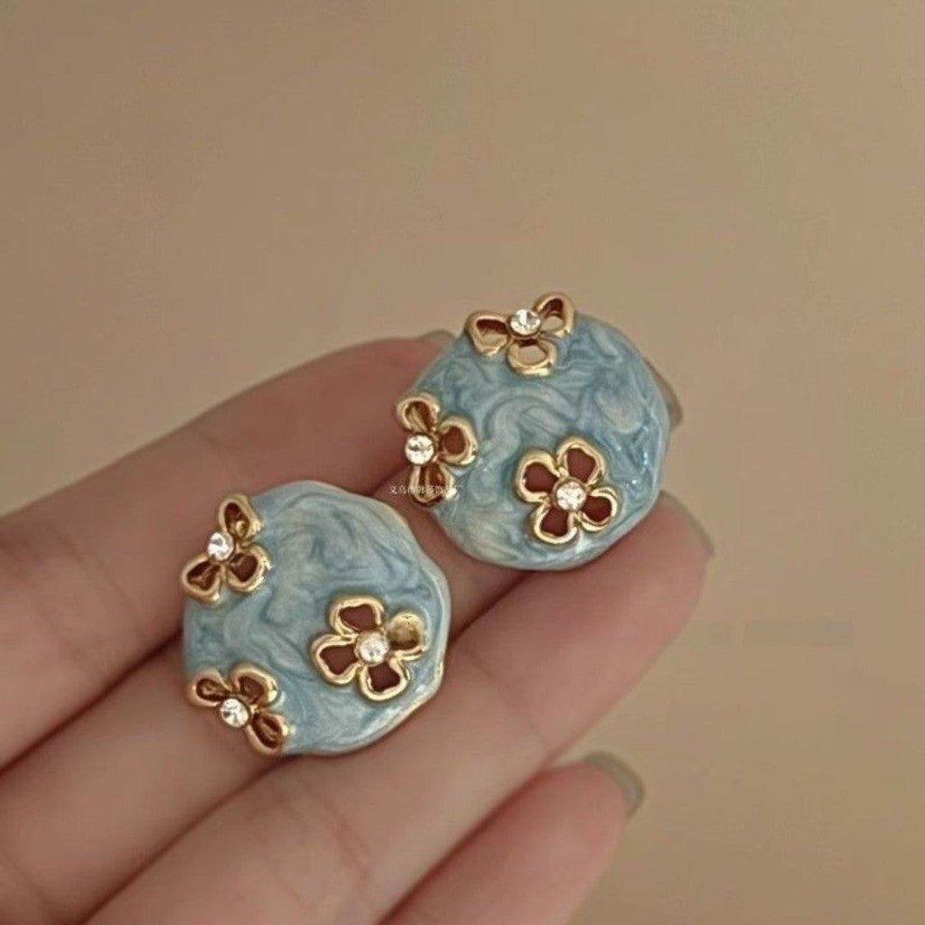 Aretes stud celestes con flores doradas.